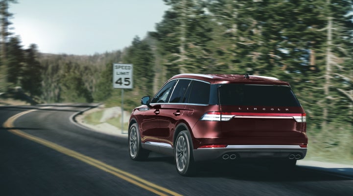 A 2024 Lincoln Aviator® SUV is being driven on a winding mountain road | Varsity Lincoln in Novi MI