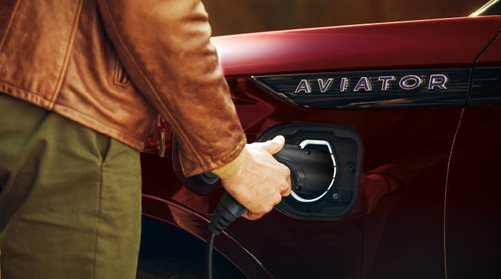 A hand is shown plugging in the charger into the charging port of a 2021 Lincoln Aviator | Varsity Lincoln in Novi MI