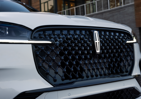 The black grille of a white 2025 Lincoln Aviator® SUV is shown with its fog lights on. | Varsity Lincoln in Novi MI