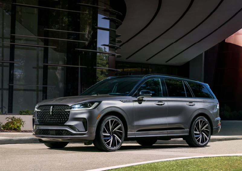 A gray 2025 Lincoln Aviator® SUV is parked outside a modern building showcasing the driver’s side of the vehicle. | Varsity Lincoln in Novi MI