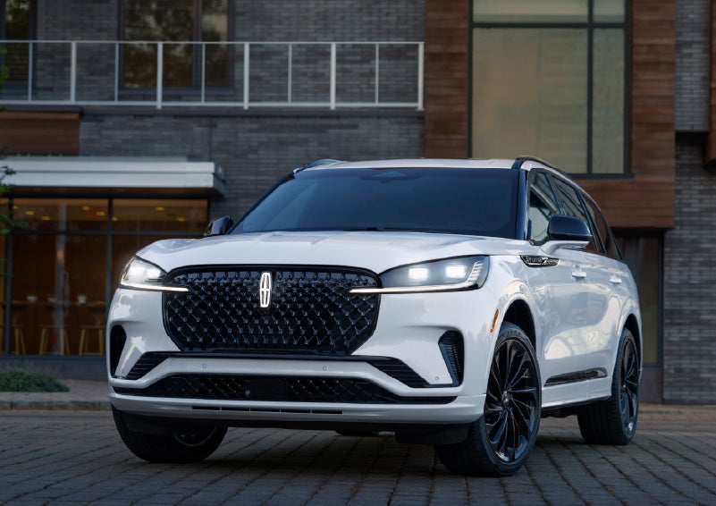 A 2026 Lincoln Aviator® Reserve model is shown with the available Jet Appearance Package parked near a restaurant. | Varsity Lincoln in Novi MI