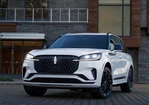 A 2026 Lincoln Aviator® Reserve model is shown with the available Jet Appearance Package parked near a restaurant. | Varsity Lincoln in Novi MI