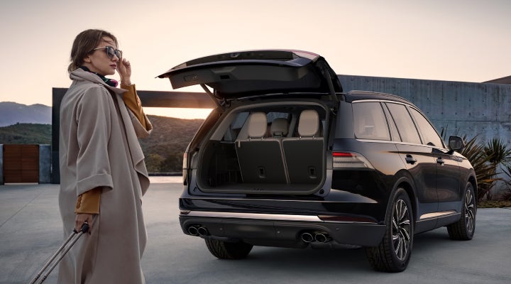 A woman approaches a 2026 Lincoln Aviator® SUV with its rear liftgate open. | Varsity Lincoln in Novi MI