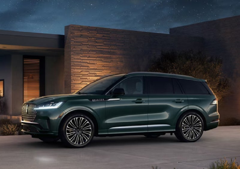 A green 2027 Lincoln Aviator® SUV is parked outside a contemporary home. | Varsity Lincoln in Novi MI