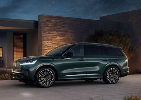 A green 2027 Lincoln Aviator® SUV is parked outside a contemporary home. | Varsity Lincoln in Novi MI