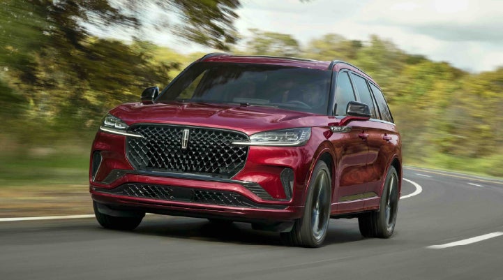 A 2027 Lincoln Aviator® SUV is being driven on a country road | Varsity Lincoln in Novi MI