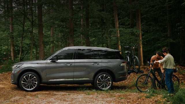A father and son load e-bikes on a bike rack attached to a 2027 Lincoln Aviator® SUV. | Varsity Lincoln in Novi MI