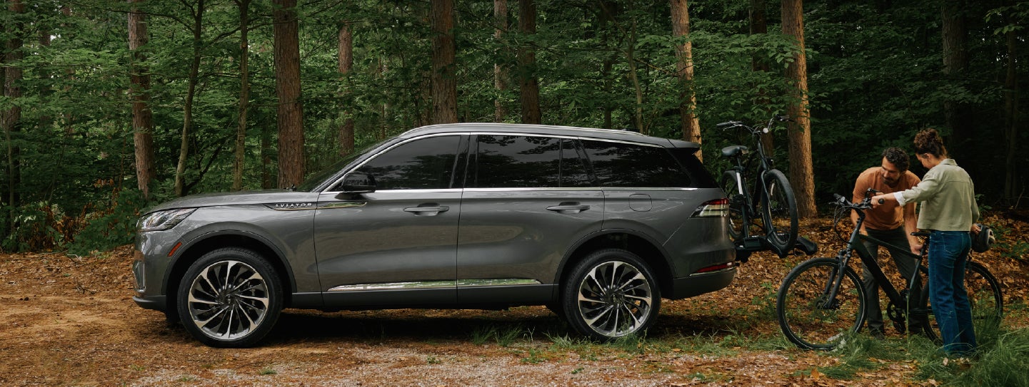 A father and son load e-bikes on a bike rack attached to a 2027 Lincoln Aviator® SUV. | Varsity Lincoln in Novi MI